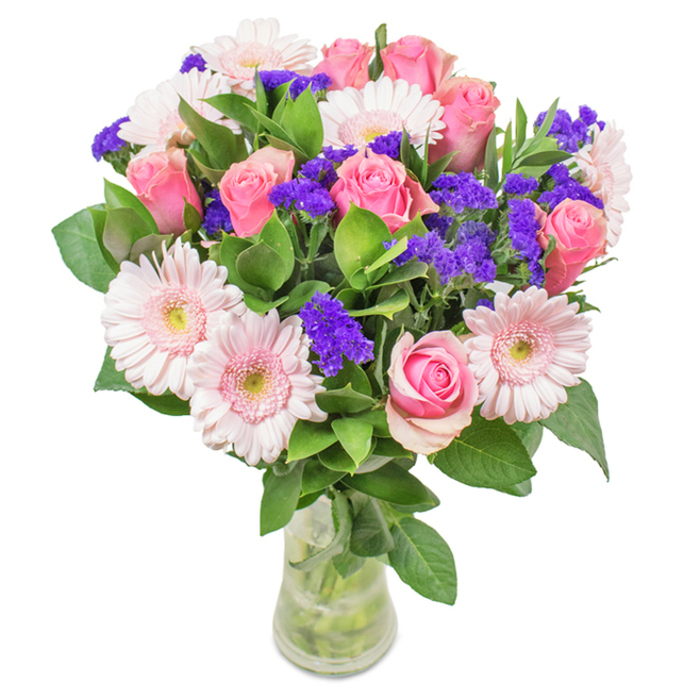 Presented in a crystal-clear glass vase against a pristine white background, this floral arrangement is a stunning composition of roughly seven to nine pink roses-both tightly furled and gently unfurling. Their spiral centers exude romance and subtle drama, woven gracefully with five to seven pale pink gerbera daisies whose broad, radiant heads and nearly silvery centers capture soft natural light. Pops of vivid purple statice introduce striking texture and chromatic contrast, reminiscent of summer florals seen around West Wickham Common. Abundant dark green foliage interlaces through the design, providing both structure and freshness, and forming a lush carpet at the base. The transparent vase, displaying water-kissed stems, completes the tableau with delicacy and a sense of new beginnings. Perfect for celebratory occasions like anniversaries, birthdays, Mother's Day, or as a signature accent in a West Wickham home or office, this thoughtfully arranged bouquet embodies festivity, affection, and a timeless, local elegance.